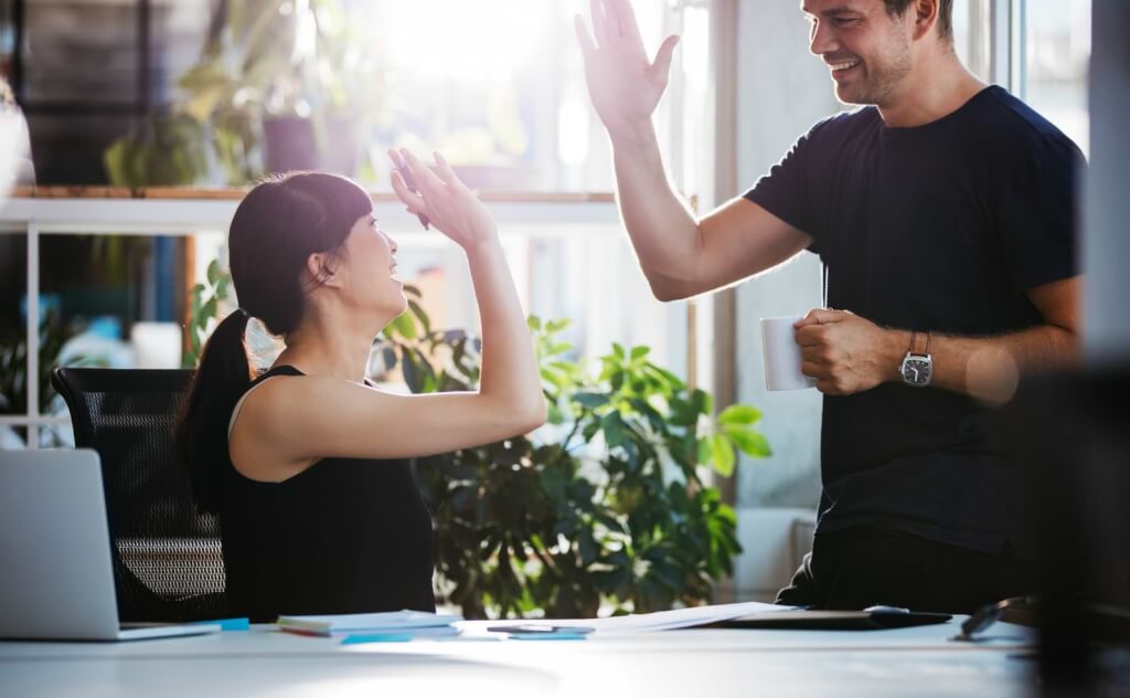 Kvinna och man gör high-five på kontor
